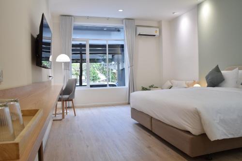 a bedroom with a bed and a desk and a window at Squirrel House in Bang Rak