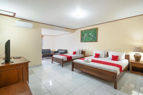 a hotel room with two beds and a television at RedDoorz Plus at Mahajaya Hotel Denpasar in Denpasar