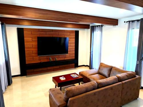a living room with a couch and a flat screen tv at Baan Suan Sawan Villa in Krabi town