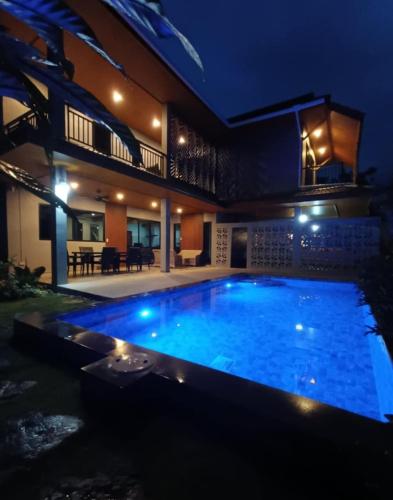 a swimming pool in front of a house at night at Baan Suan Sawan Villa in Krabi town