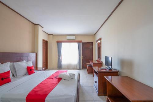 a bedroom with a bed and a desk and a television at RedDoorz Plus at Mahajaya Hotel Denpasar in Denpasar