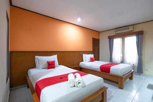 two beds in a hotel room with shoes on them at RedDoorz Plus at Mahajaya Hotel Denpasar in Denpasar