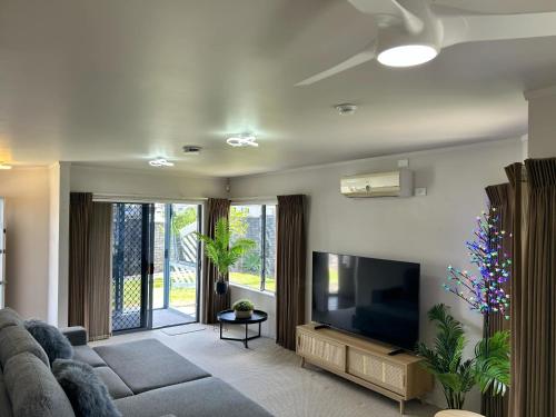 a living room with a couch and a flat screen tv at Central Whangarei Townhouse in Whangarei