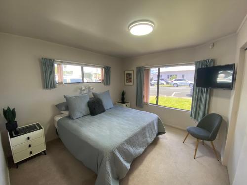 a bedroom with a bed and a window and a television at Central Whangarei Townhouse in Whangarei