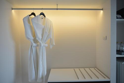 a closet with white clothes hanging on a rack at Le D'Tel Bangkok in Bangkok
