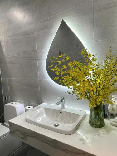a bathroom with a sink and a vase of yellow flowers at Sky View Memory Inn in Xuan An