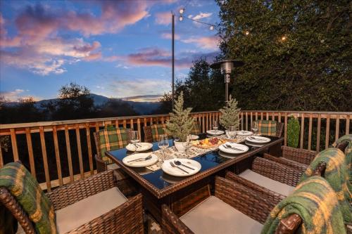 a wooden table with plates of food on a deck at Sequoia's Dream with Mountain View, Spa, Heated Floor, Bar, Cinema! in Oakhurst
