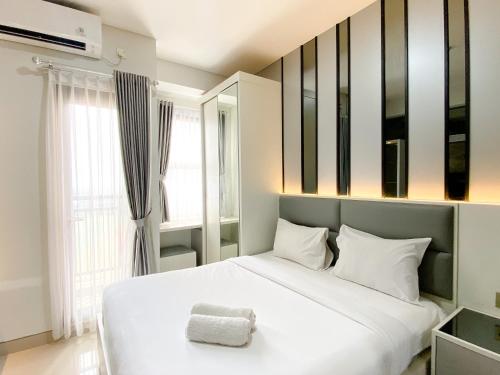a bedroom with a large white bed and a mirror at Best Deal and Cozy Studio Room Transpark Cibubur Apartment By Travelio in Depok