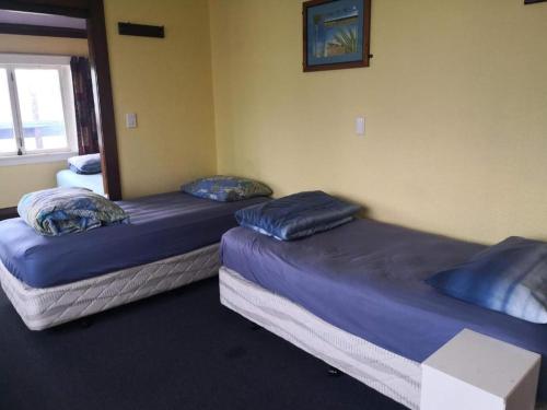 two twin beds in a room with a window at Rotorua Central Backpackers in Rotorua