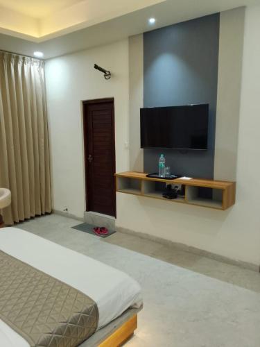 a bedroom with a bed and a flat screen tv at The Grand View in Baijnāth