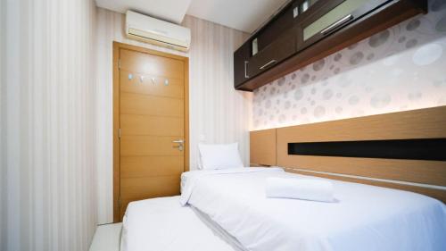 2 letti in una piccola camera con porta di Homey and Cozy Living 2BR Apartment at Aryaduta Residence Surabaya By Travelio a Surabaya