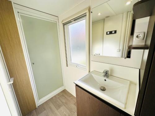 une salle de bain avec un lavabo, un miroir et une fenêtre dans l'établissement Toppyholidays Camping de Pujol in Argele's-Sur-Mer, à Argelès-sur-Mer