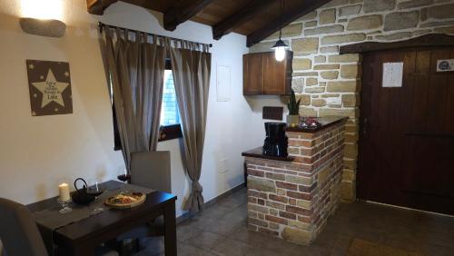 a living room with a table and a brick fireplace at Studio apartment Cami - Cottage with a soul in Gračišće
