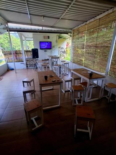 a room with tables and chairs and a flat screen tv at Kebun Teduh Sukaharja Cijeruk Bogor in Palasari