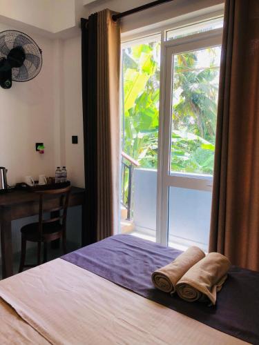a bedroom with a window with towels on a bed at Devon Surf . Inn - Hiriketiya in Dickwella