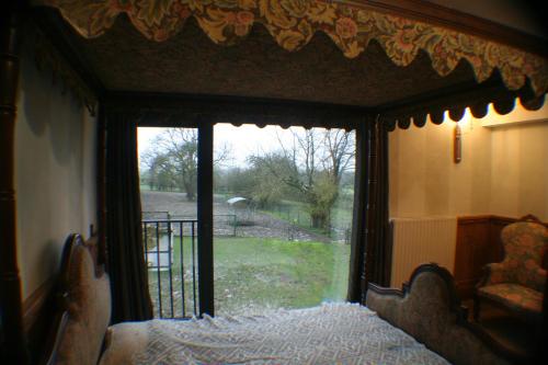 a bedroom with a bed with a view of a yard at B&B Le Relais de Charlinette in Boignée