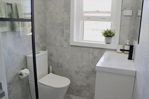 a bathroom with a white toilet and a window at Luxe Newly Renovated 2 Bed Unit - WALK TO BEACH in Wollongong