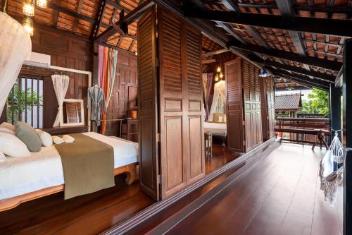 a bedroom with a bed in a room with wooden walls at Authentic Thai Villa with Open-Air Living & Pool-Central-Huahin in Hua Hin