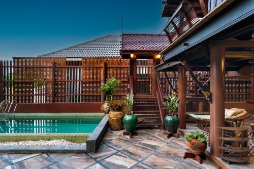 a house with a swimming pool on a patio at Authentic Thai Villa with Open-Air Living & Pool-Central-Huahin in Hua Hin