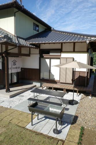 Kawatanaにあるくつろ郷Kutsuro-goの家の前にテーブルと傘付きのパティオ