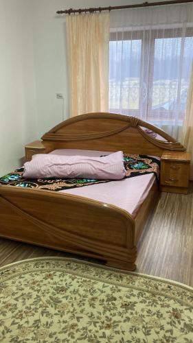 a large wooden bed in a room with a window at Trai bun in Maramures in Fereşti