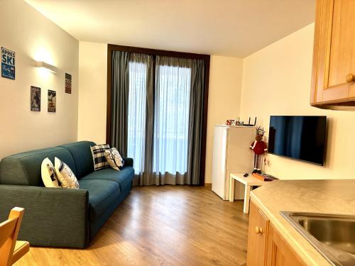a living room with a blue couch in a kitchen at La Stella Bilocale con balcone in Ponte di Legno