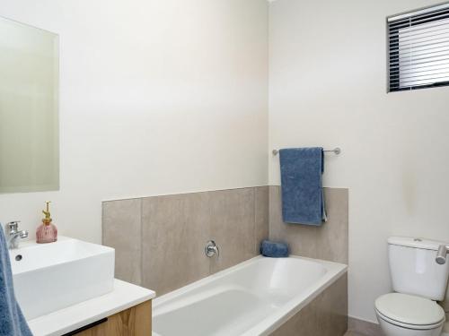 a bathroom with a tub and a toilet and a sink at Sunset Haven in Midrand