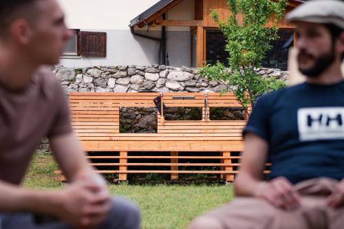 two men sitting in the grass in front of a house at Hostel Kronotop in Triglav National Park in Log pod Mangartom
