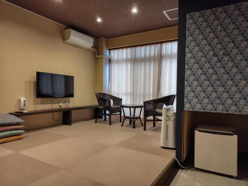 a room with a table and chairs and a television at Wa no oto 和の音交流館 鬼怒川宿 in Nikko