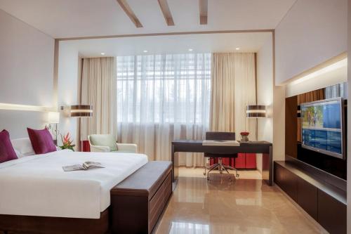 a bedroom with a bed and a desk and a television at The Abdali Boulevard Hotel in Amman