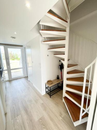 un escalier dans une maison aux murs blancs et au parquet dans l'établissement Maisonnette de charme - Refaite à neuf - Vue mer, à Guidel