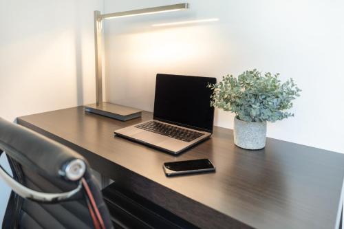 a desk with a laptop and a phone and a plant at Garner Hotel Berlin - Mitte by IHG in Berlin