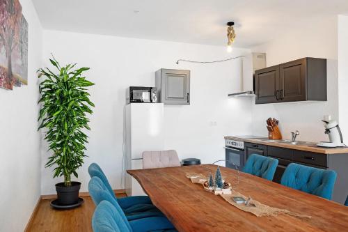 a kitchen and dining room with a wooden table and blue chairs at White House Apartments in Kappel-Grafenhausen