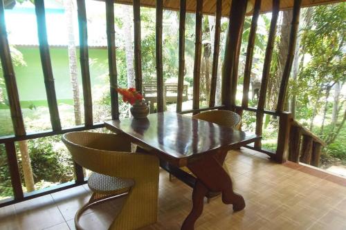 a wooden table and chairs in a room with windows at Tontarn Resort and Spa in Khanom