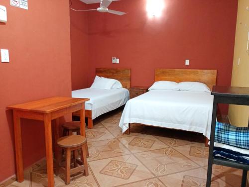 a room with two beds and a table and a table at Hospedaje casa Yuca in Valladolid