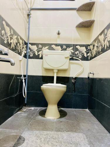 a toilet in a bathroom with black and white tiles at Esha Enclave - Premium Suits in Bengaluru