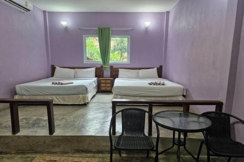 a room with two beds and a table and chairs at Tontarn Resort and Spa in Khanom