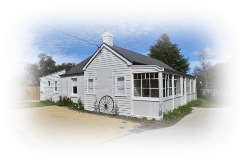 a white house with a black roof at The Baker's Cottage in the Heart of Richmond Sleeps 6 in Hobart