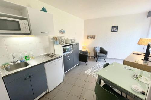 une petite cuisine avec un évier et un micro-ondes dans l'établissement Charmante maisonnette Bord de mer Terrasse, à Guidel