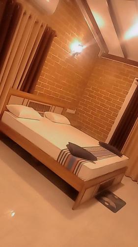 un grand lit dans une pièce avec un mur de briques dans l'établissement Minara Guest House, à Mirissa