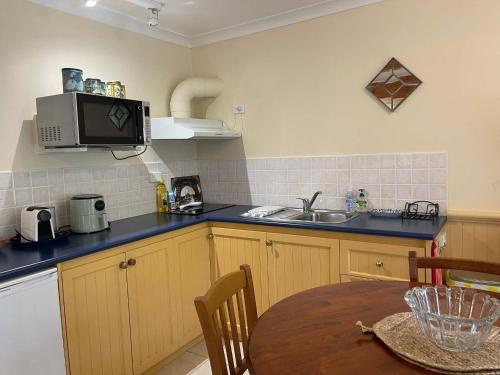 a kitchen with a table and a microwave at Banksia Cottage in Perth Hills in Perth