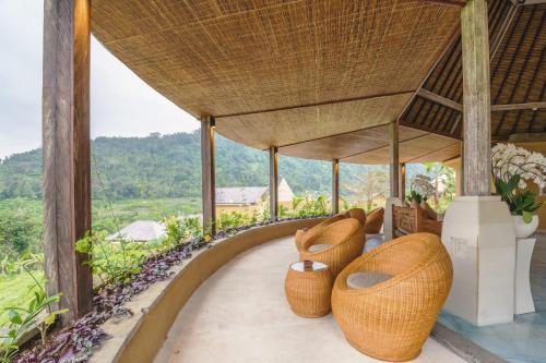 a room with wicker chairs on the balcony of a house at The Wapa Lux Tent in Sidemen