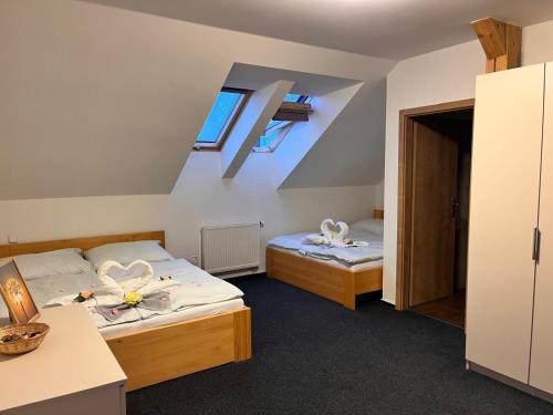 two beds in a room with two windows at Penzion a Restaurace u Sousedů in Strážný