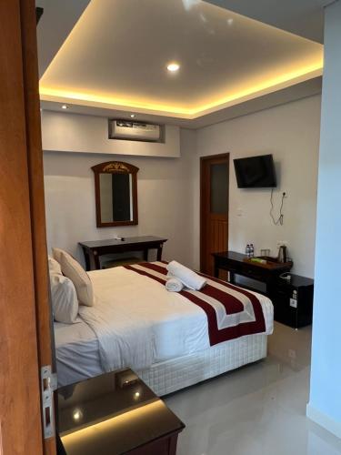 a hotel room with a bed and a television at Mandhasativa Homestay in Singaraja
