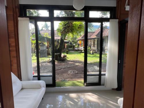 a living room with a large window looking out at a yard at Mandhasativa Homestay in Singaraja