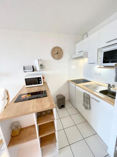 une cuisine avec des placards blancs et une horloge murale dans l'établissement Splendide T2 Archi Cocooning Vue mer 180, à Ploemeur