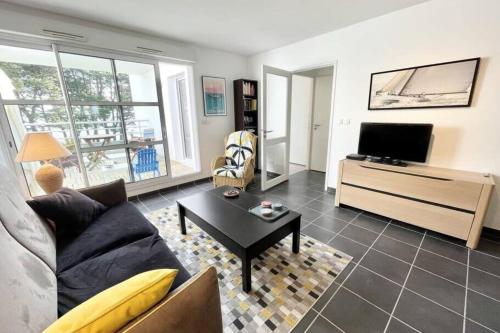 un salon avec un canapé et une télévision dans l'établissement Charmant T2 Top Cosy Face à la rade, à Larmor-Plage