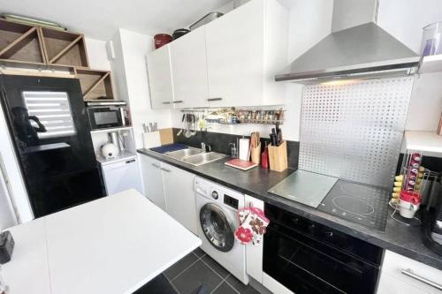 La cuisine est équipée de placards blancs et d'un four avec plaques de cuisson noires. dans l'établissement Charmant T2 Top Cosy Face à la rade, à Larmor-Plage