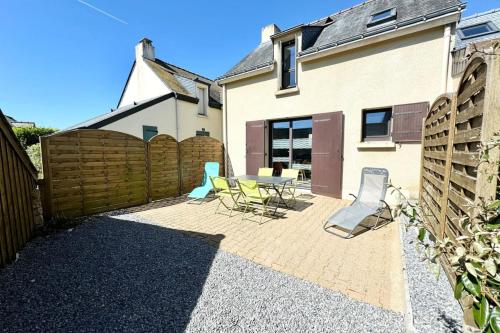 un patio avec une table et des chaises et une clôture dans l'établissement Charmante maisonnette Terrasse - Proche plages, à Guidel
