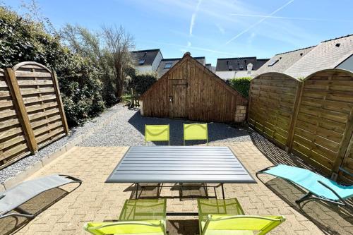un patio avec une table et des chaises et une clôture dans l'établissement Charmante maisonnette Terrasse - Proche plages, à Guidel